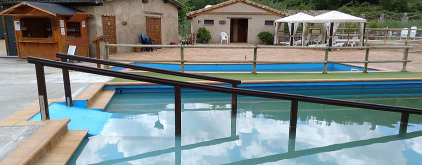 alt="Instalaciones exteriores con piscina accesible y rampa adaptada frente a casas rurales y zona de descanso."