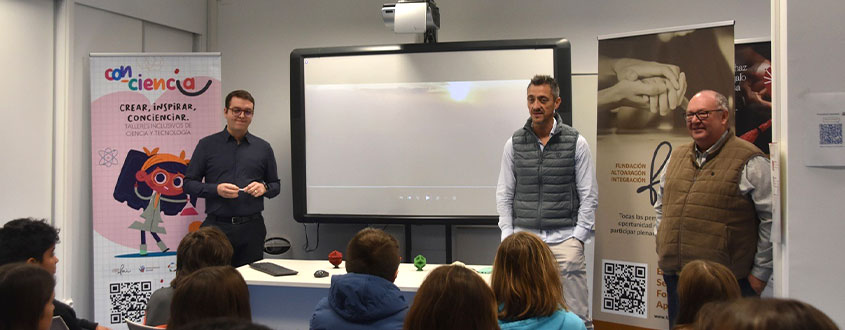 alt="Tres ponentes presentan una actividad educativa de ciencia y tecnología ante un grupo de estudiantes en un aula."